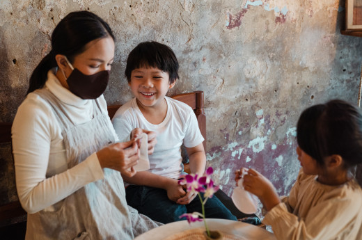 Cheerful woman putting masks on children