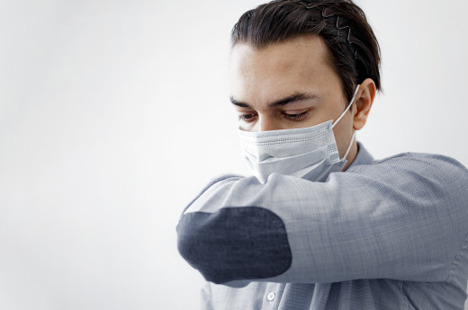 Sick man is coughing into his sleeves or elbow