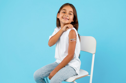 Happy Vaccinated Kid Girl Showing Arm After Vaccination, Blue Background